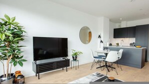 A modern living room with a flat-screen TV, a dining area with chairs, a small table, and a potted plant. - Coopers Cross Two by Dublin At Home (Dublin)