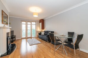 A modern living room with a glass dining table, black chairs, a sofa, and a fireplace. - Holywell Rise Swords (Swords)