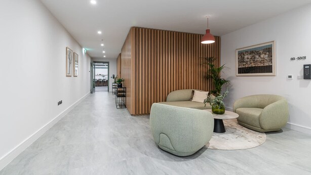 Un interior moderno con un separador de madera, un sofá, una silla y una mesita.