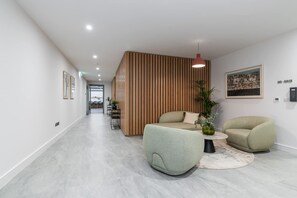 Un interior moderno con un separador de madera, un sofá, una silla y una mesita.