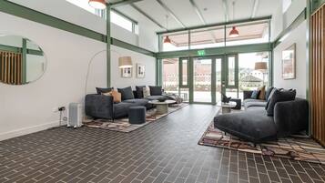A spacious lobby with a brick floor, grey sofas, and a large mirror.