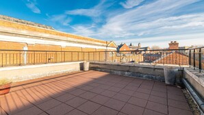 A rooftop terrace with a tiled floor, metal railing, and a view of buildings in the background. - Dean Swift Square by Dublin At Home (Dublin)