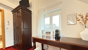 Ein Hotelzimmer mit einem Holzschrank, einer Kaffeemaschine, einem Wasserkocher und einer weißen Badewanne.