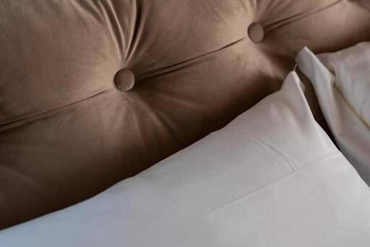 A bed with a headboard featuring tufted buttons and a white pillow.