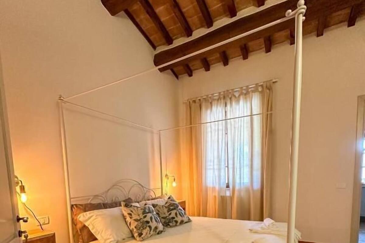 A four-poster bed in a room with a tiled floor and a wooden ceiling.