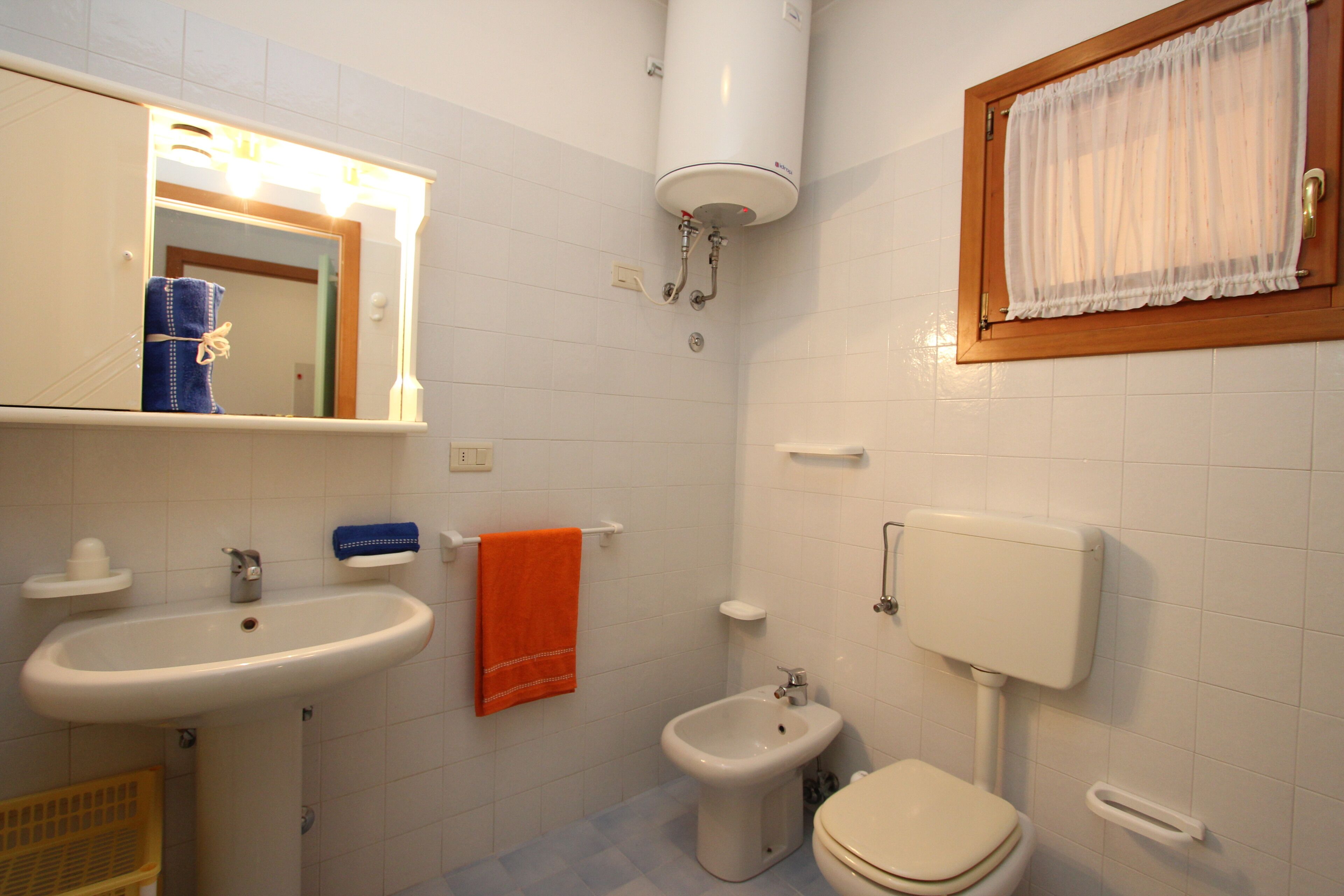 Un bagno con lavandino, bidet, WC e uno specchio con un asciugamano appeso al muro.