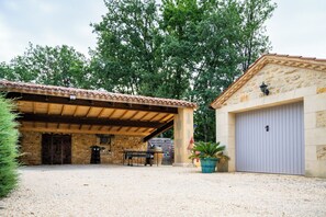 Un espacio al aire libre techado con un muro de piedra, una mesa de madera y una puerta de garaje.
