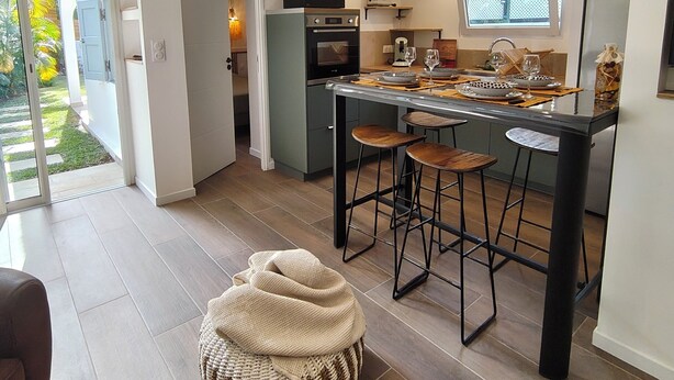 A modern kitchen with a central island, bar stools, and a built-in oven. - The Bird of Paradise (Entre-Deux)