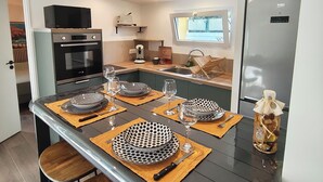 A compact kitchen with a central island, built-in appliances, and a window providing natural light. - The Bird of Paradise (Entre-Deux)