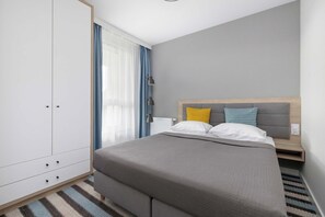 A bedroom with a bed, a wardrobe, a bedside table, and a lamp. - Family Apartment | Parking | Close to the Beach (Międzyzdroje)