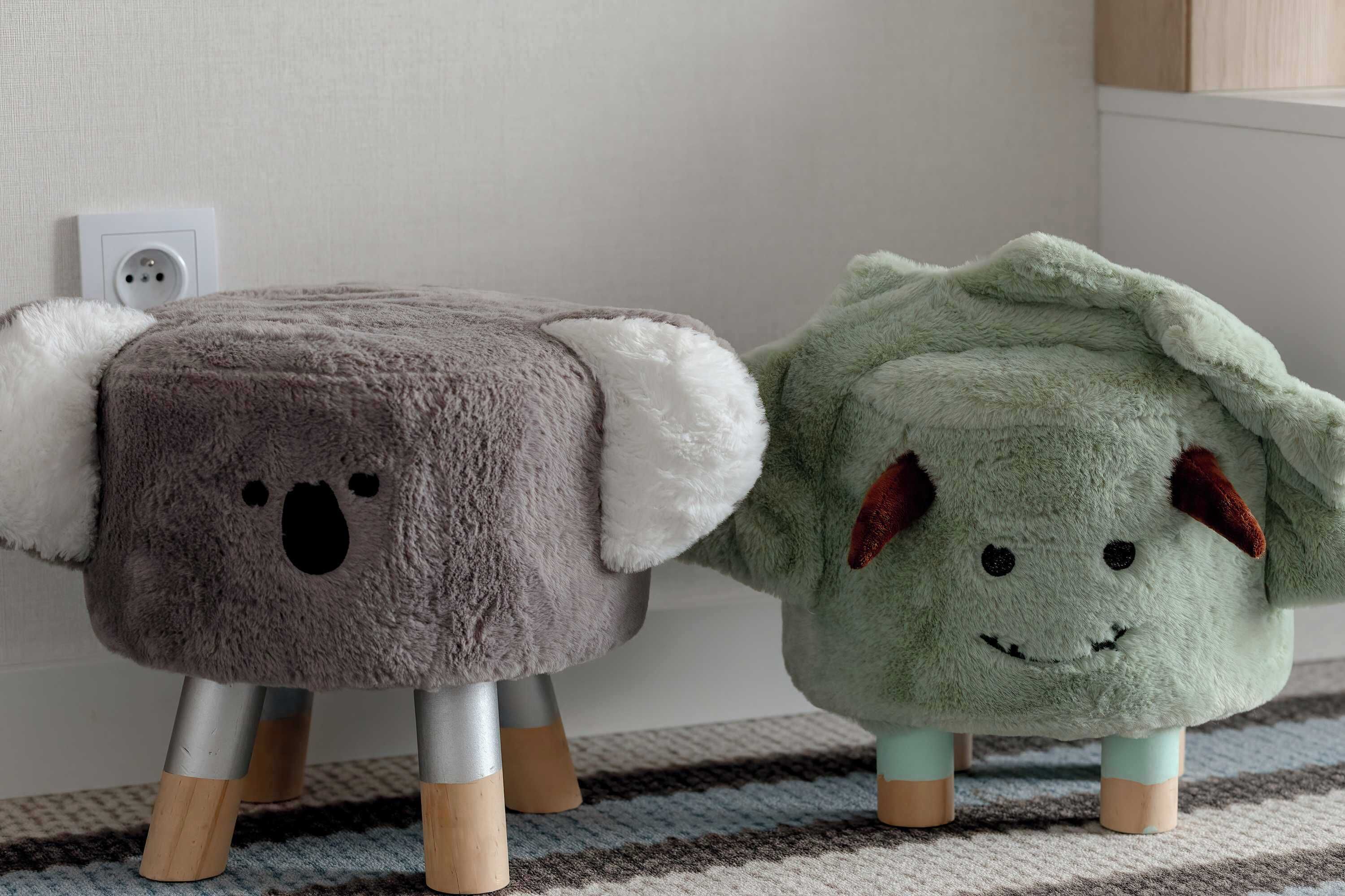 Two plush toy sheep with wooden legs standing on a patterned rug.