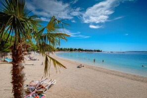 A beach with palm trees, sun loungers, and a clear blue sky. - La Perla - Downtown House (Omiš)