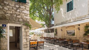 An outdoor cafe area with stone walls, wooden tables, and benches. - La Perla - Downtown House (Omiš)