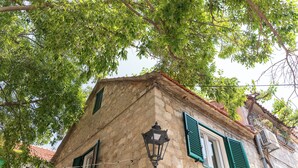A corner building with a stone facade, green shutters, and a street lamp. - La Perla - Downtown House (Omiš)