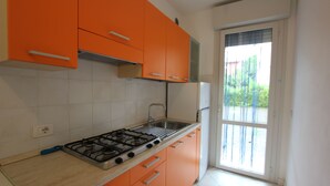 Una cocina con gabinetes naranja, una estufa a gas y una ventana con vista a la vegetación.