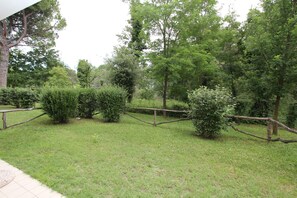 A grassy area with a wooden fence and various trees. - Green Retreat by the Beach (San Michele al Tagliamento)