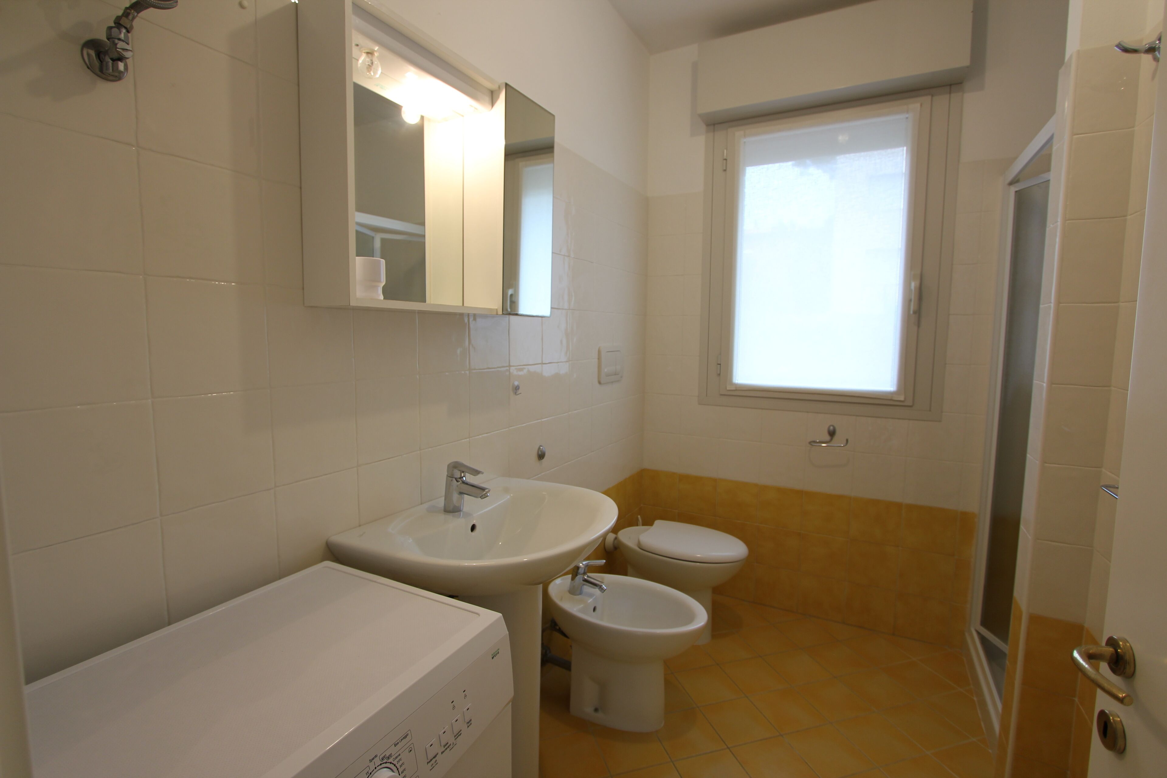 A bathroom with a sink, bidet, toilet, and a shower area.
