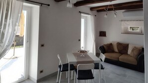 Ein modernes Wohnzimmer mit Essbereich, mit freiliegenden Holzbalken, einer Couch und einem Tisch mit Stühlen.
