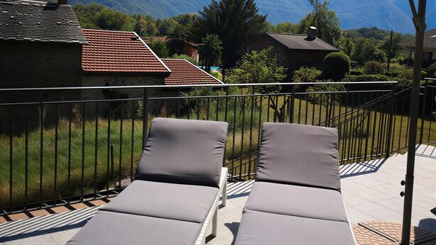 Eine Terrasse mit zwei Liegestühlen und Blick auf Berge.