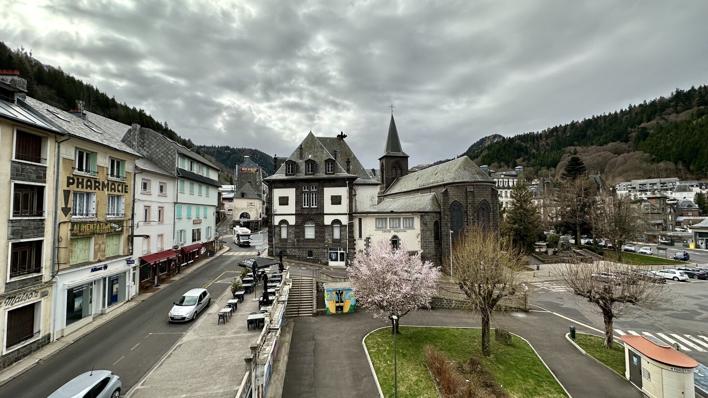 Ein Stadtplatz mit einem historischen Gebäude, einer Apotheke und einer Kirche.