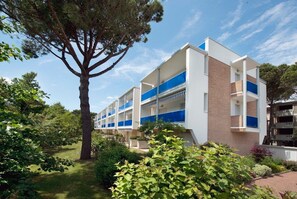 Ein mehrstöckiges Gebäude mit moderner Architektur, mit Balkonen und einem Garten.