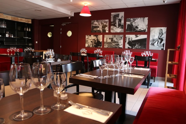 A restaurant interior with multiple tables set for dining, each with wine glasses and cutlery.