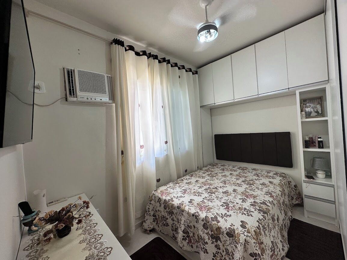 Een slaapkamer met een bed, een airconditioning, een kledingkast en een nachtkastje met een lamp.