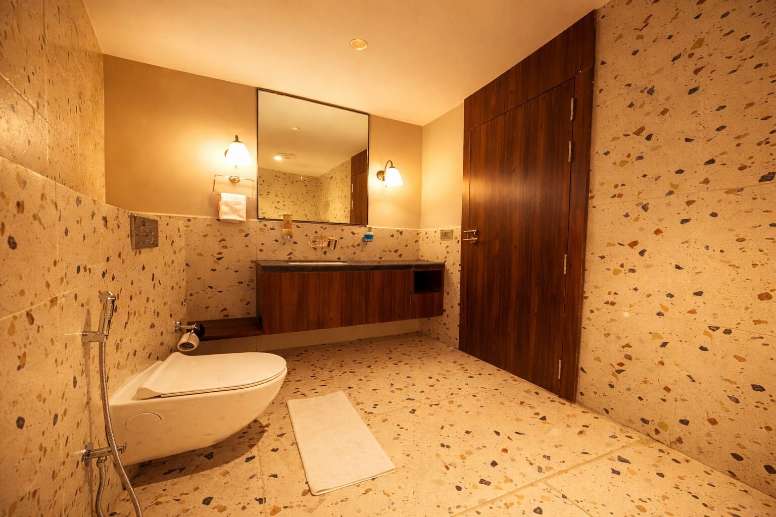 A bathroom with a freestanding toilet, a sink, a mirror, and a shower.