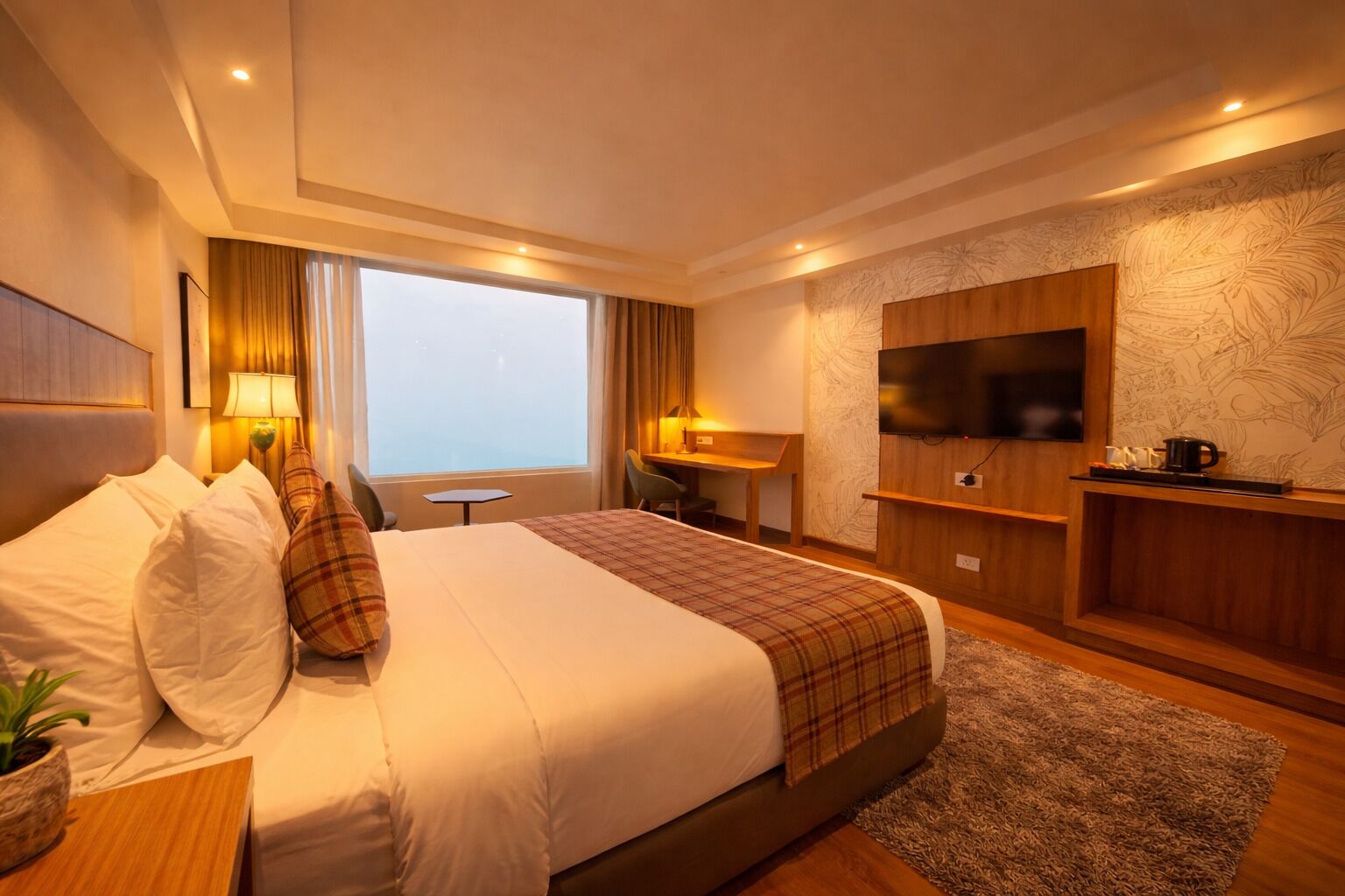 Habitación de hotel con una cama grande, escritorio, televisión y vistas de la ciudad.