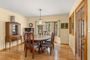 A dining area with a wooden table, chairs, a chandelier, a cabinet, and a painting.
