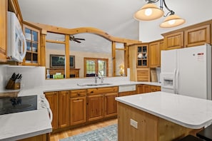 A kitchen with wooden cabinets, a white refrigerator, a built-in oven, and a large window.