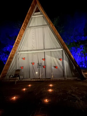 Un edificio de forma triangular con fachada de madera y una puerta de cristal grande decorada con corazones.