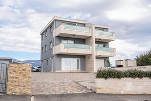 Ein mehrgeschossiges Wohngebäude mit modernem Design, inklusive Balkone, Garage und befestigter Auffahrt.