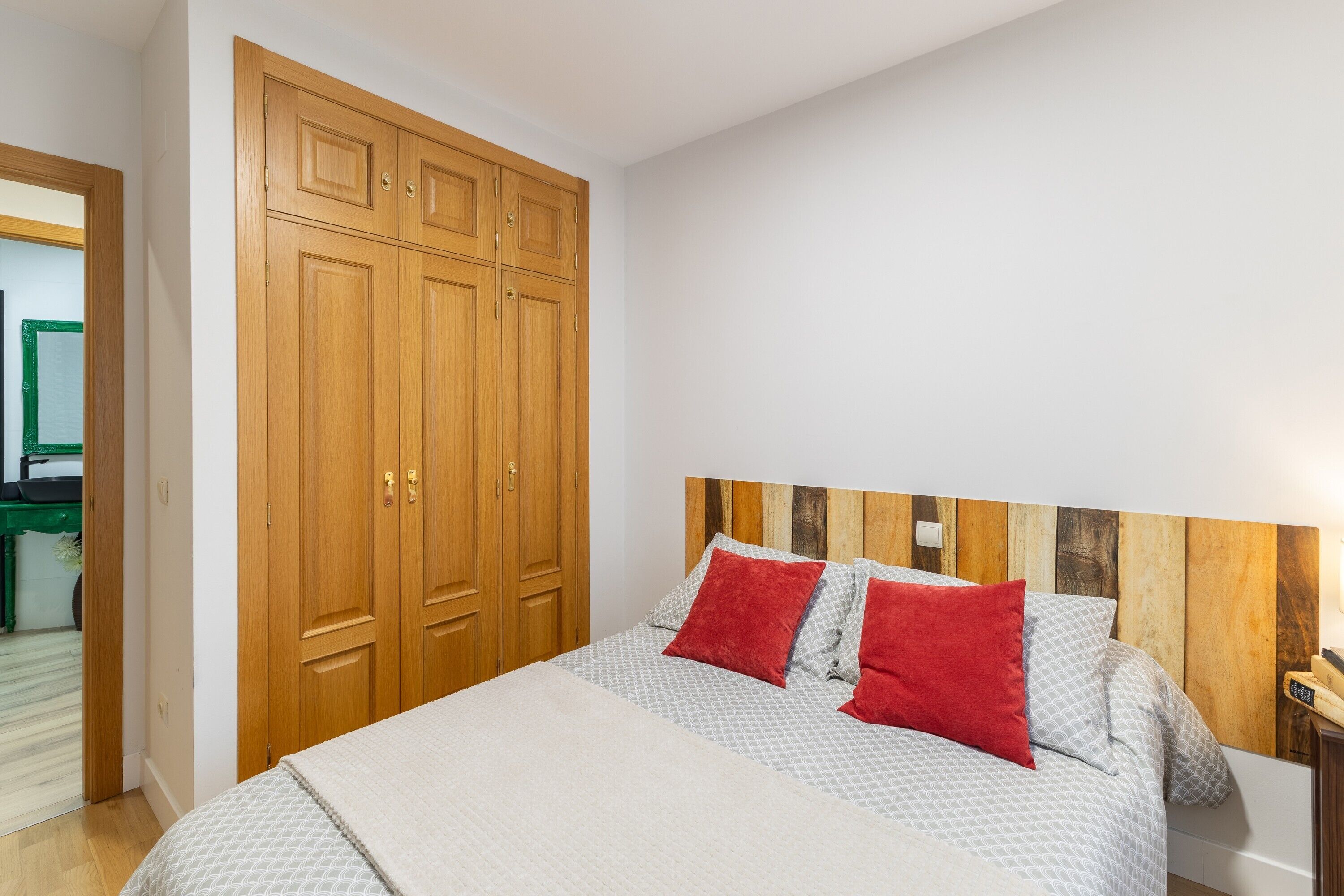 Ein Schlafzimmer mit Bett, Holzschrank und einem Kopfteil mit Holzpaneelen.
