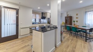 Eine moderne Küche mit einer zentralen Kochinsel, einem Essbereich mit Stühlen und Blick auf den angrenzenden Wohnraum.
