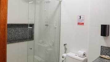 Un baño moderno con ducha envuelta en vidrio, inodoro con toalla y encimera de granito.