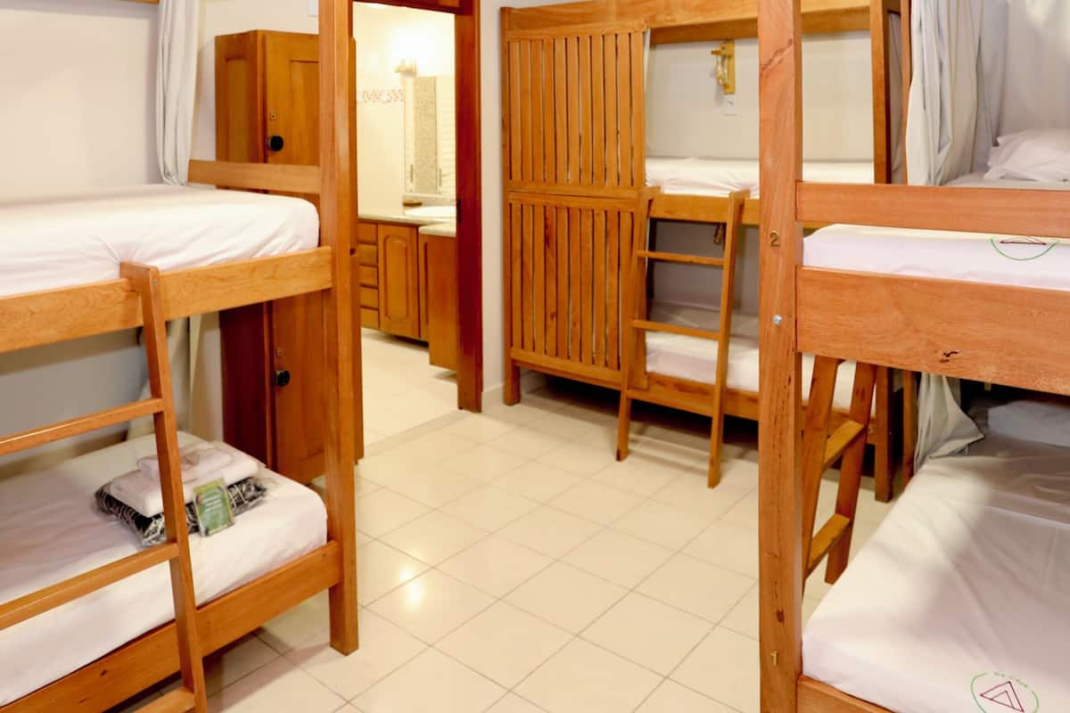 A room with bunk beds, wooden cabinets, and a tiled floor.