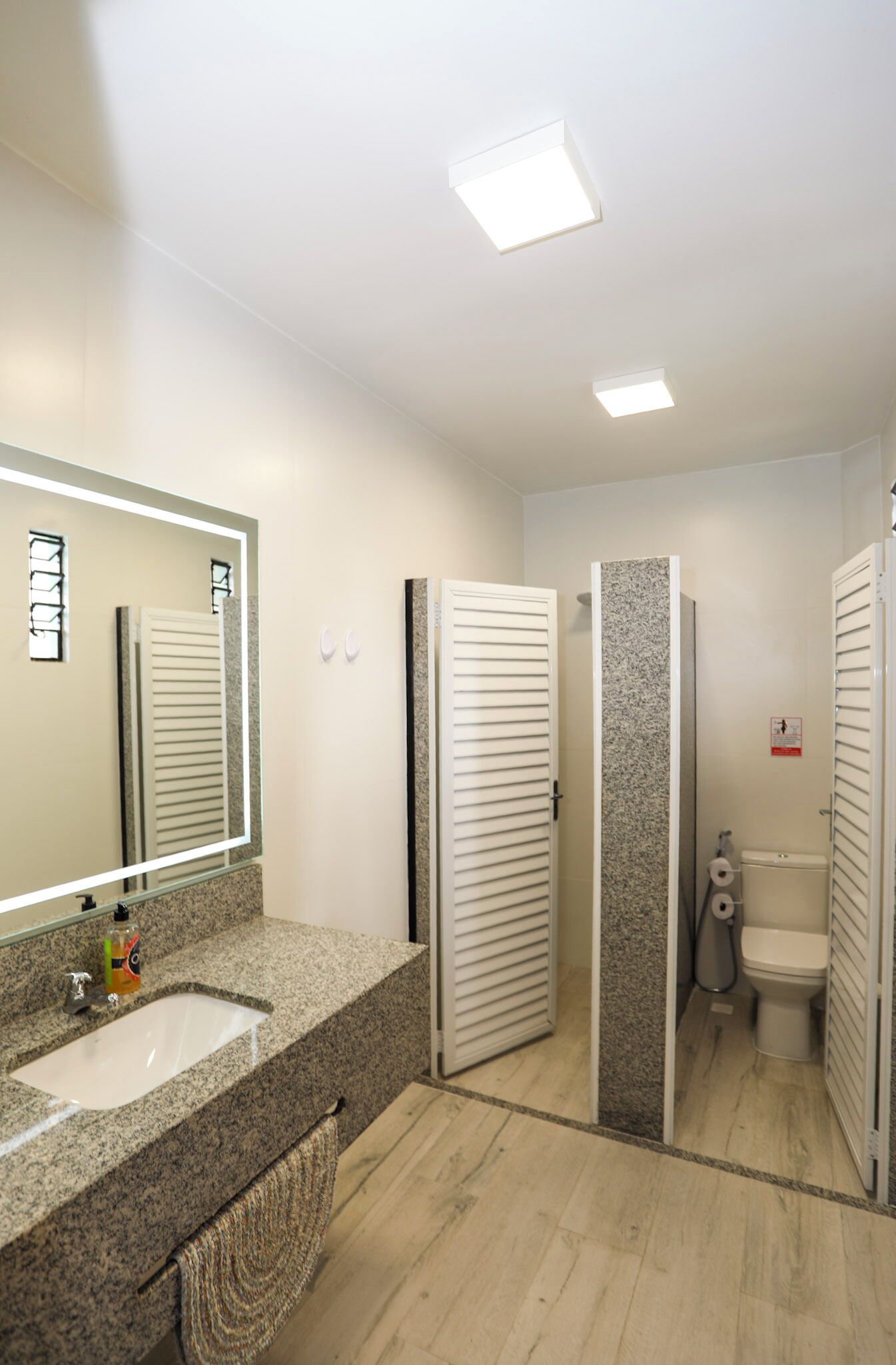 Un bagno con lavabo su piano in granito, specchio, WC e cabina doccia.