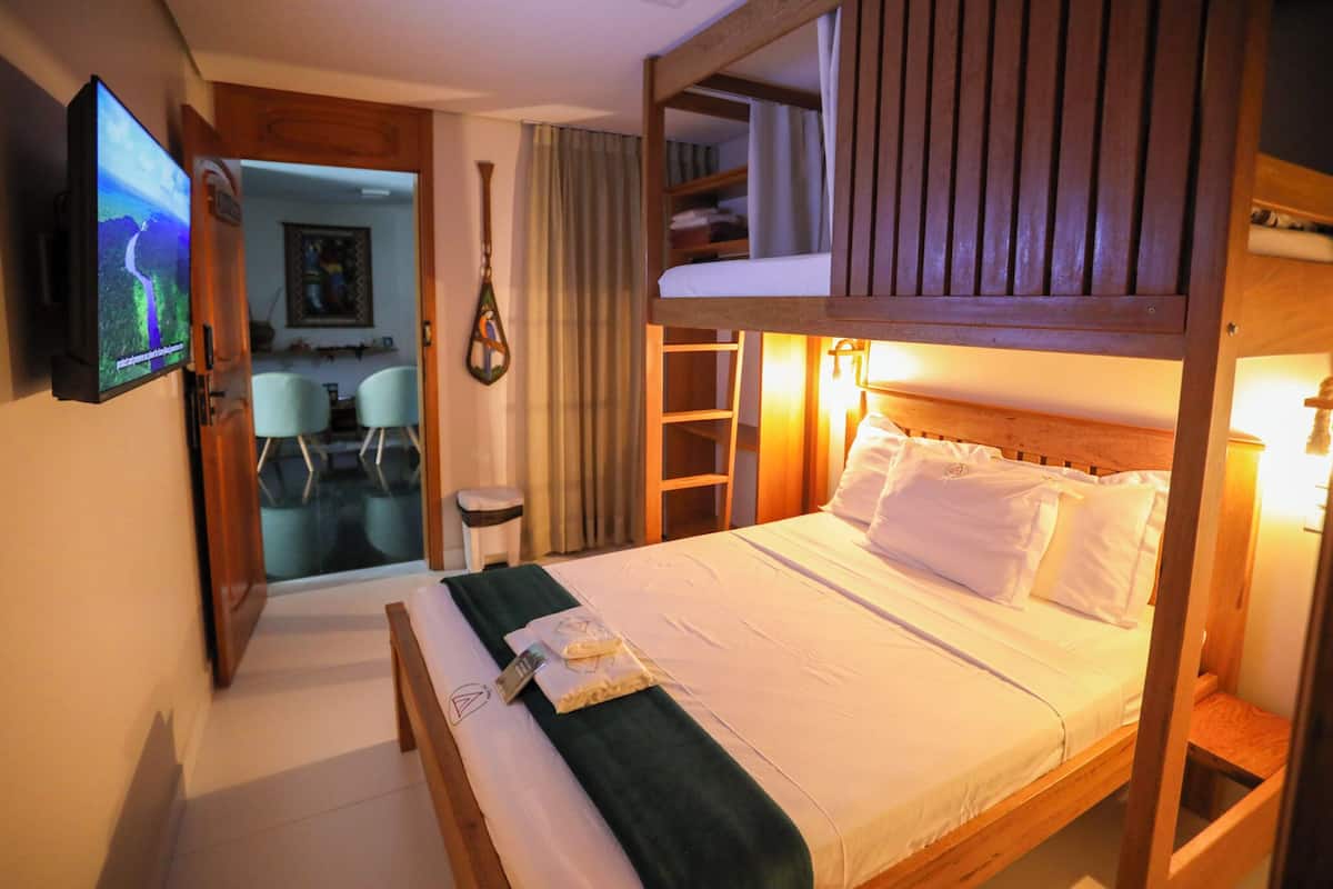 A bunk bed room with a TV, a small table, and a chair.
