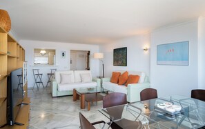 A modern living room with a sofa, chairs, a glass dining table, and a TV. - NEW!!! El Coloso Beachfront Complex: views, pools, parking, Benalmadena Costa (Benalmadena)