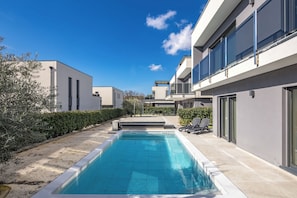 A modern poolside area with a rectangular pool, adjacent lounge chairs, and a clear blue sky. - Villa Centinera With Private Pool (Medulin)
