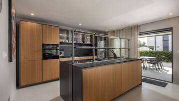 Een moderne keuken met houten kastjes, een centraal eiland en een eethoek met een tafel en stoelen.