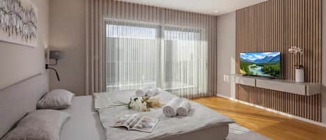 Ein modernes Schlafzimmer mit einem Bett, einem Fernseher und Blick auf eine Berglandschaft.