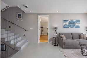 A modern living room with a staircase, a grey sofa, a coffee table, and a painting on the wall. - Villa Centinera With Private Pool (Medulin)