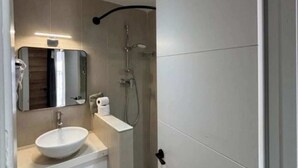 A modern bathroom with a white sink, mirror, and shower. - Apartment 1 beach Almayate (Almayate Bajo)
