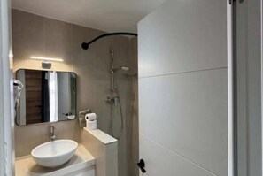 Un bagno moderno con lavandino, specchio e doccia bianchi.