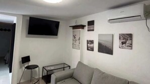 A living room with a sofa, a TV mounted on the wall, and a small table. - Apartment 1 beach Almayate (Almayate Bajo)
