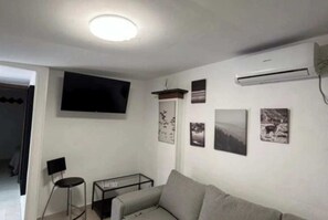 Un soggiorno con un divano, una TV a parete e un tavolino.