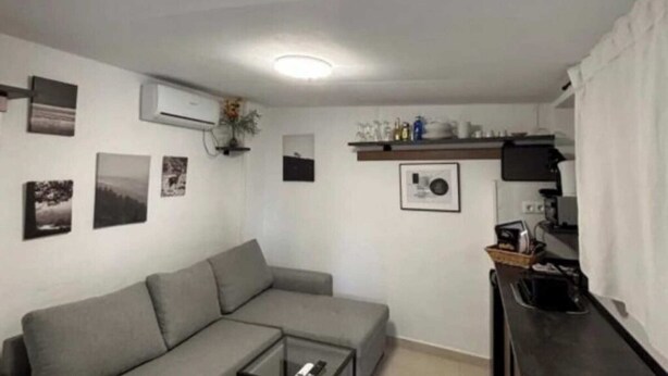 A living area with a sofa, a coffee table, and a kitchen area with a counter and cabinets. - Apartment 1 beach Almayate (Almayate Bajo)