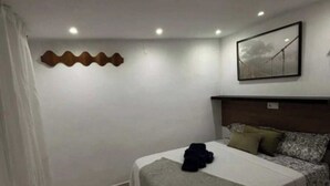 A hotel room with a bed, a headboard, a wall-mounted artwork, and a curtain. - Apartment 1 beach Almayate (Almayate Bajo)